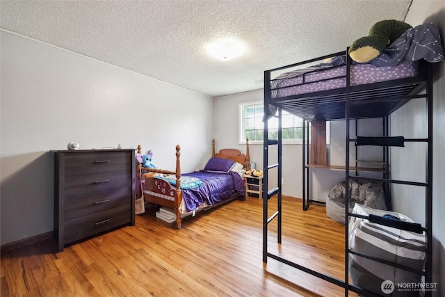 bedroom with baseboards, a textured ceiling, and wood finished floors