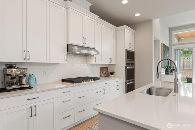 6346 Marymere Rd SW, Port Orchard, WA 98367 - kitchen with under cabinet range hood, appliances with stainless steel finishes, tasteful backsplash, white cabinets, and light countertops