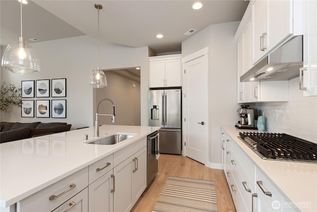 6346 Marymere Rd SW, Port Orchard, WA 98367 - kitchen featuring appliances with stainless steel finishes, under cabinet range hood, light wood-type flooring, white cabinetry, and tasteful backsplash