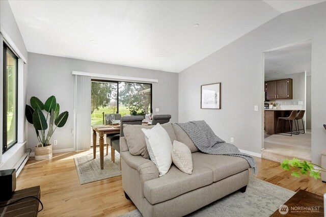 living area with baseboards, lofted ceiling, and light wood-style flooring