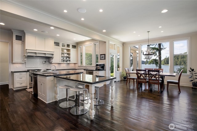 1220 Madrona Beach Rd NW, Olympia, WA 98502 - kitchen featuring custom range hood, dark countertops, plenty of natural light, and a center island with sink