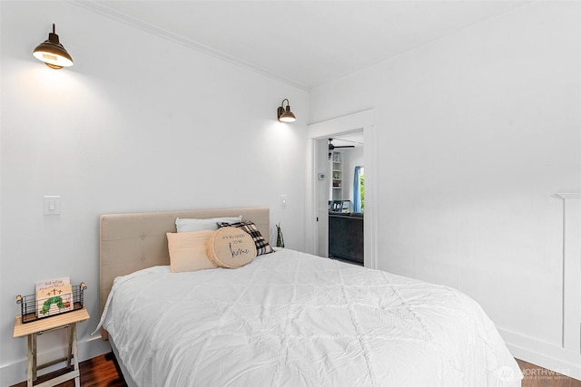 bedroom with wood finished floors, baseboards, and crown molding