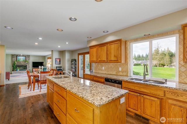 kitchen with a center island with sink, a sink, light stone counters, and dishwasher