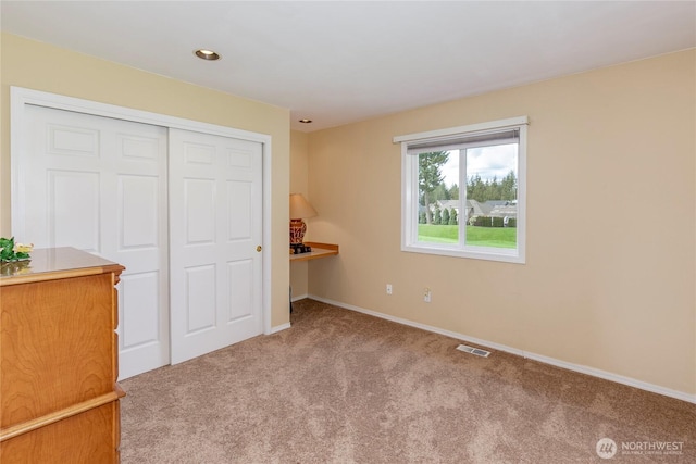 unfurnished bedroom with baseboards, visible vents, a closet, and carpet floors