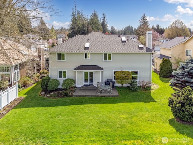 back of property featuring fence, a chimney, french doors, a yard, and a patio area