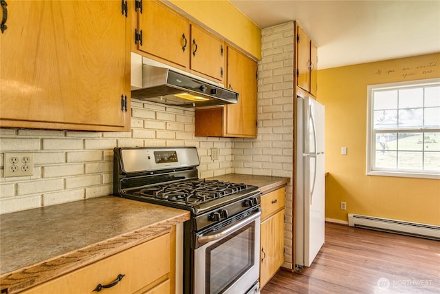 5296 Olson Rd, Ferndale, WA 98248 - kitchen featuring stainless steel gas range, freestanding refrigerator, under cabinet range hood, backsplash, and a baseboard radiator