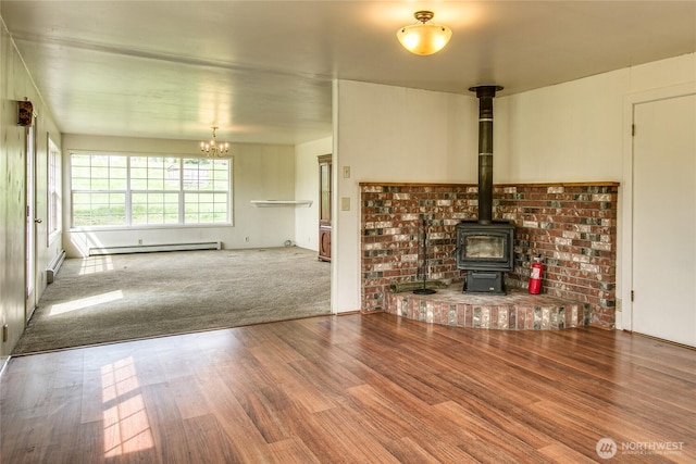 5296 Olson Rd, Ferndale, WA 98248 - unfurnished living room featuring a baseboard heating unit, a chandelier, a wood stove, wood finished floors, and a baseboard radiator