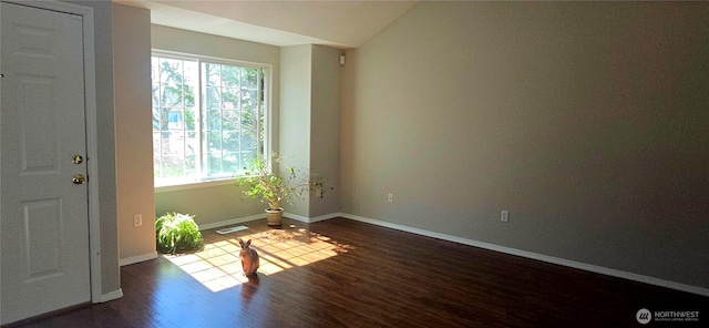 empty room with baseboards, visible vents, and dark wood-style flooring