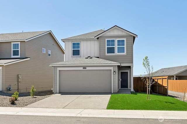 view of front facade with a shingled roof, fence, concrete driveway, and a front yard