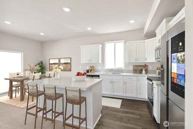 kitchen featuring white cabinets, stainless steel appliances, a center island, and light countertops