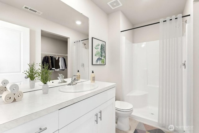 bathroom featuring toilet, vanity, a stall shower, and visible vents