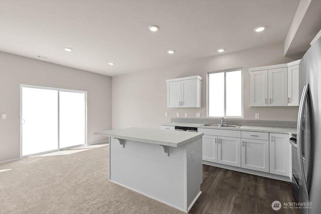 kitchen featuring light countertops, recessed lighting, a kitchen island, a sink, and white cabinets