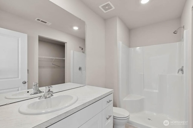 full bathroom with toilet, vanity, a shower stall, and visible vents