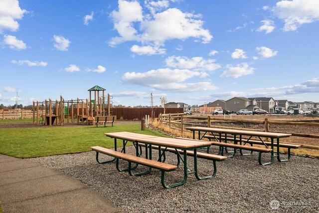 view of home's community featuring playground community, fence, and a lawn