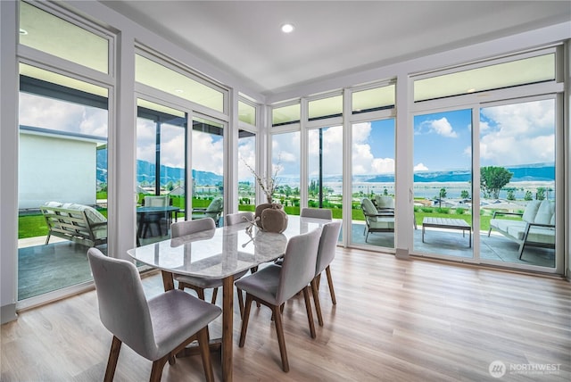 sunroom / solarium with floor to ceiling windows, wood finished floors, recessed lighting, and a water view
