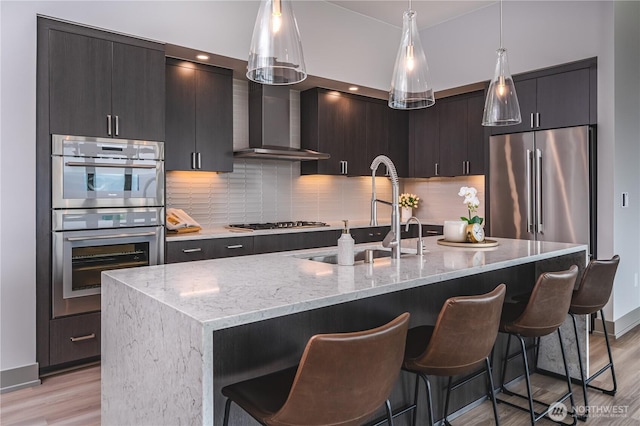 kitchen with appliances with stainless steel finishes, a breakfast bar, light wood-style floors, and a sink