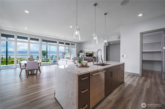 kitchen with hanging light fixtures, dishwasher, a sink, dark wood-style floors, and open floor plan