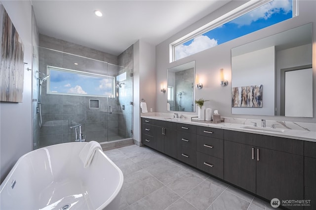 full bathroom featuring a freestanding tub, double vanity, a stall shower, and a sink