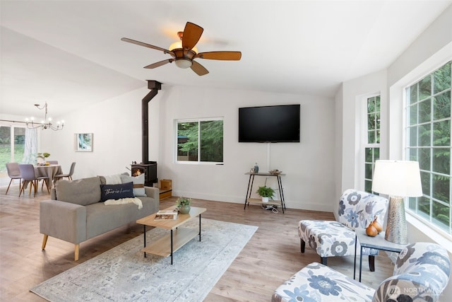 living room with a wood stove, lofted ceiling, plenty of natural light, wood finished floors, and baseboards