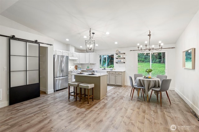 kitchen with stainless steel refrigerator, a chandelier, a kitchen island, recessed lighting, and light wood finished floors