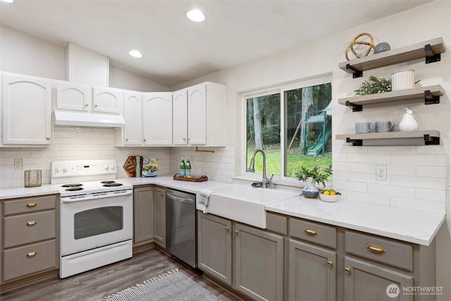 kitchen with electric stove, dishwasher, a sink, under cabinet range hood, and gray cabinetry