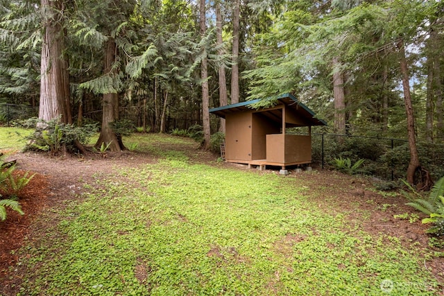 view of yard featuring an outbuilding, a shed, and a wooded view