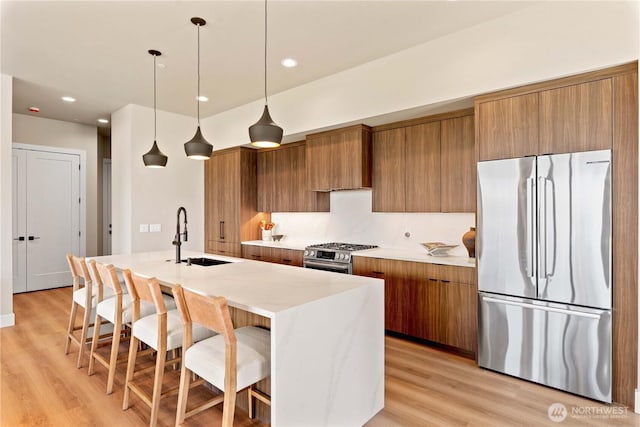 9604 Ridgeview Dr NW, Quincy, WA 98848 - kitchen featuring stainless steel appliances, brown cabinets, a sink, a center island with sink, and recessed lighting