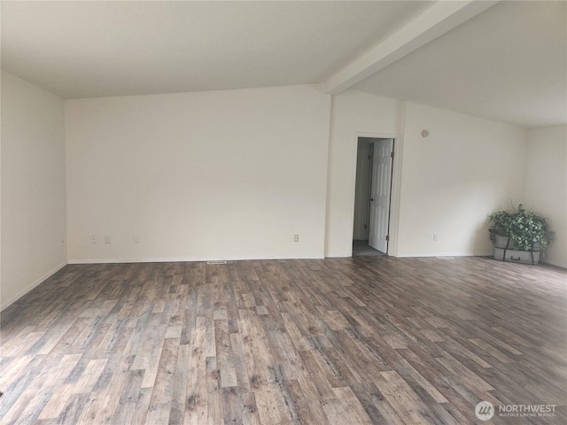 empty room with wood finished floors, lofted ceiling with beams, and baseboards