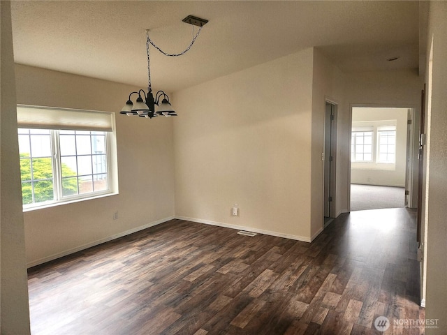 unfurnished dining area with dark wood-style floors, an inviting chandelier, and baseboards