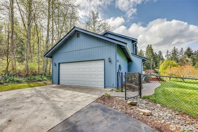view of property exterior featuring an attached garage, concrete driveway, fence, and a lawn