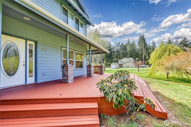 wooden terrace featuring a porch and a lawn