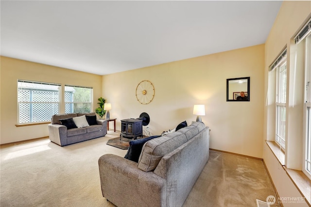 living room with visible vents, a wood stove, baseboards, and carpet