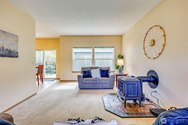 living area featuring carpet floors, a wood stove, and baseboards