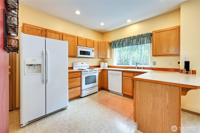 kitchen with light countertops, white appliances, a peninsula, recessed lighting, and light floors