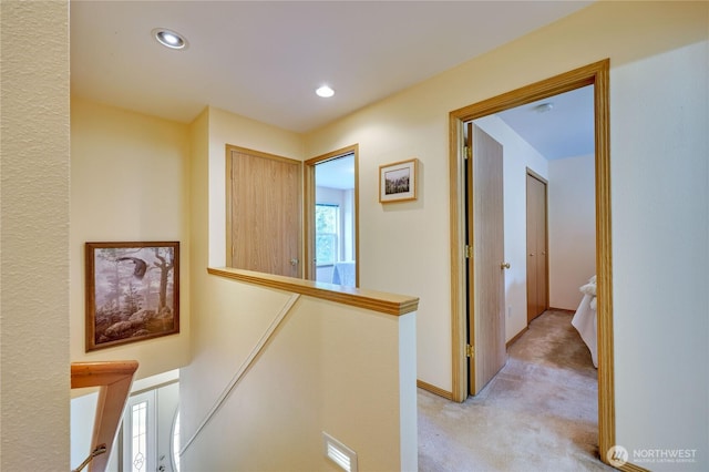 corridor featuring light carpet, baseboards, an upstairs landing, and recessed lighting