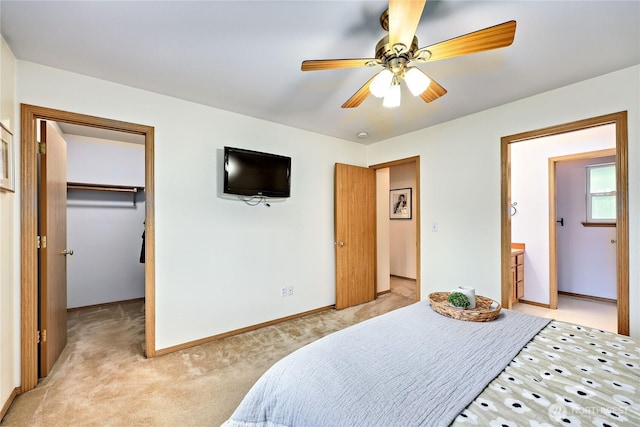 bedroom featuring a closet, baseboards, a spacious closet, ceiling fan, and light carpet