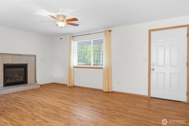 12802 Silver Dr, Anderson Island, WA 98303 - unfurnished living room featuring a tile fireplace, light wood-type flooring, baseboards, and ceiling fan