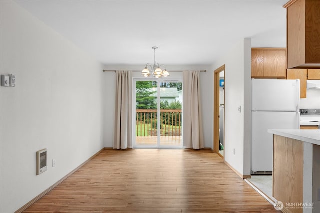 12802 Silver Dr, Anderson Island, WA 98303 - unfurnished dining area with light wood-style floors, a notable chandelier, baseboards, and heating unit