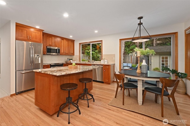 kitchen with a kitchen island, light wood-style floors, stainless steel appliances, and backsplash