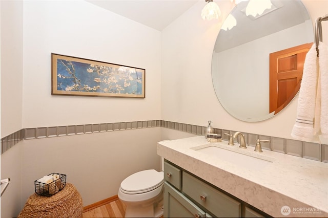 half bath featuring toilet, vanity, and wood finished floors