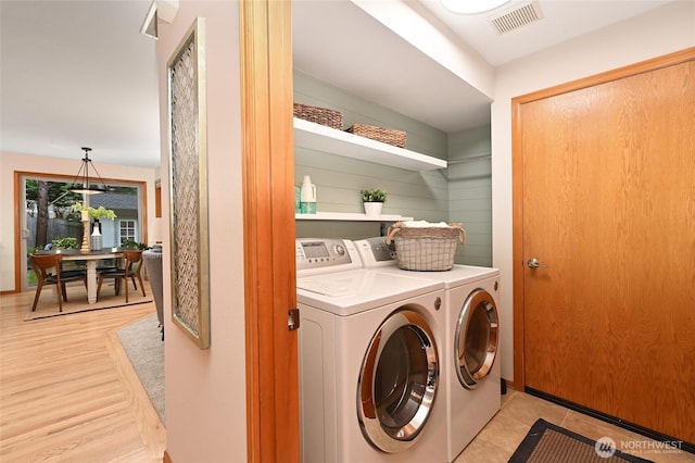 clothes washing area featuring washer and dryer, laundry area, and visible vents