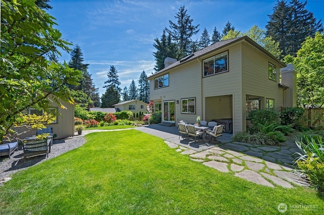 rear view of house featuring a yard, a chimney, and a patio