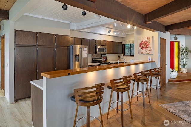 458 De Haro Ln, Friday Harbor, WA 98250 - kitchen with dark brown cabinetry, wood ceiling, light wood-type flooring, stainless steel appliances, and beamed ceiling