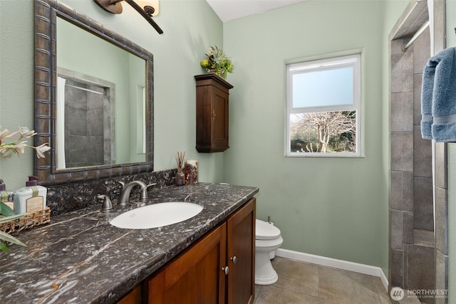 bathroom featuring vanity, toilet, baseboards, tile patterned floors, and tiled shower