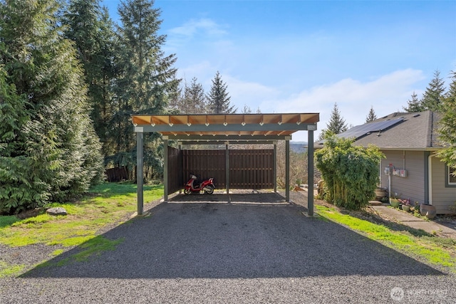exterior space featuring driveway, a detached carport, and fence