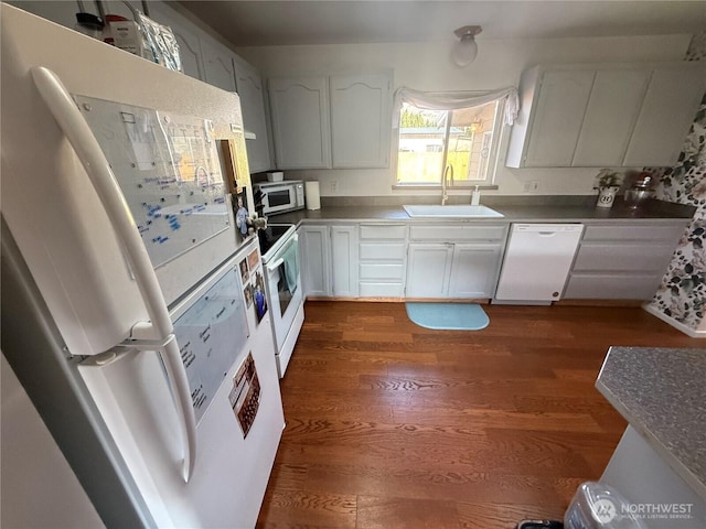 kitchen with dark wood-style floors, a sink, white cabinets, and white appliances