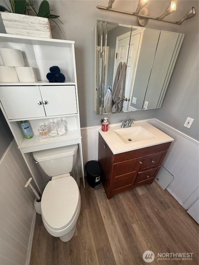 bathroom with toilet, wainscoting, wood finished floors, and vanity