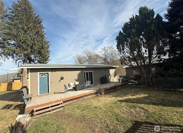 rear view of house featuring a deck, metal roof, fence, and a lawn