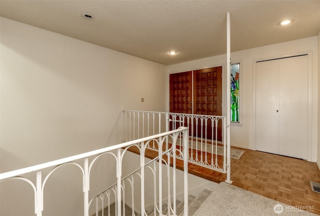 hall featuring recessed lighting, visible vents, and a textured ceiling