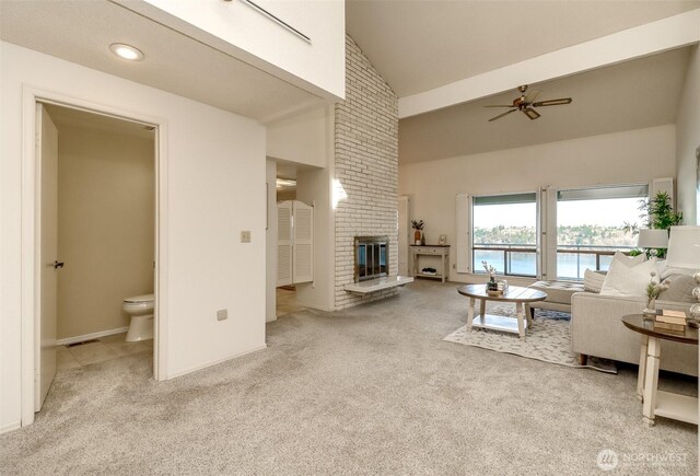 living room with a water view, high vaulted ceiling, carpet, a fireplace, and ceiling fan